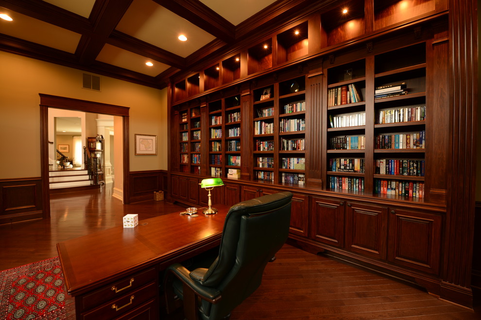 Expansive traditional study room in Indianapolis with dark hardwood floors, a freestanding desk and orange walls.