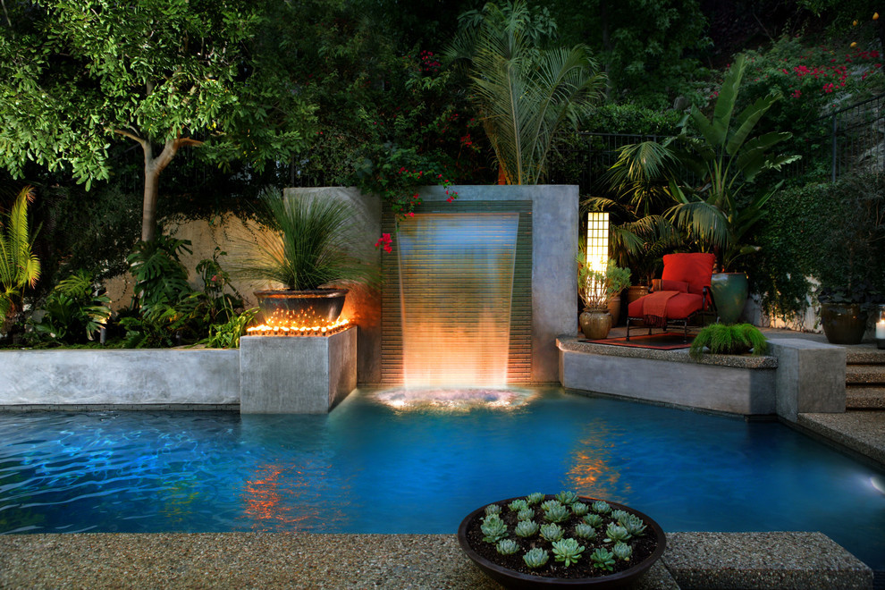 Inspiration for a mid-sized contemporary backyard custom-shaped lap pool in Los Angeles with a water feature and concrete slab.