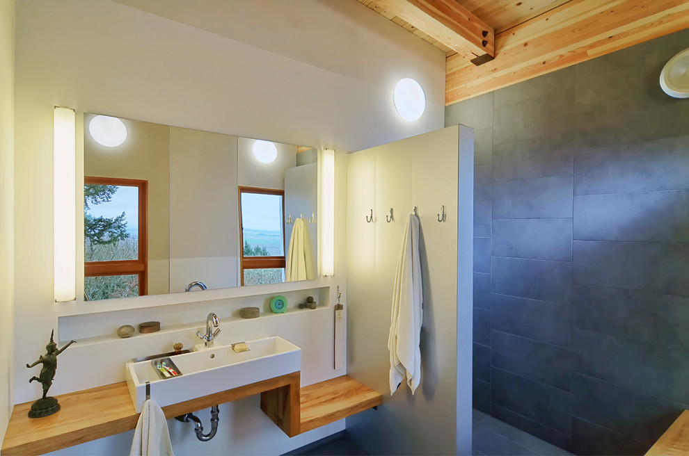 Photo of a contemporary bathroom in Other with wood benchtops.