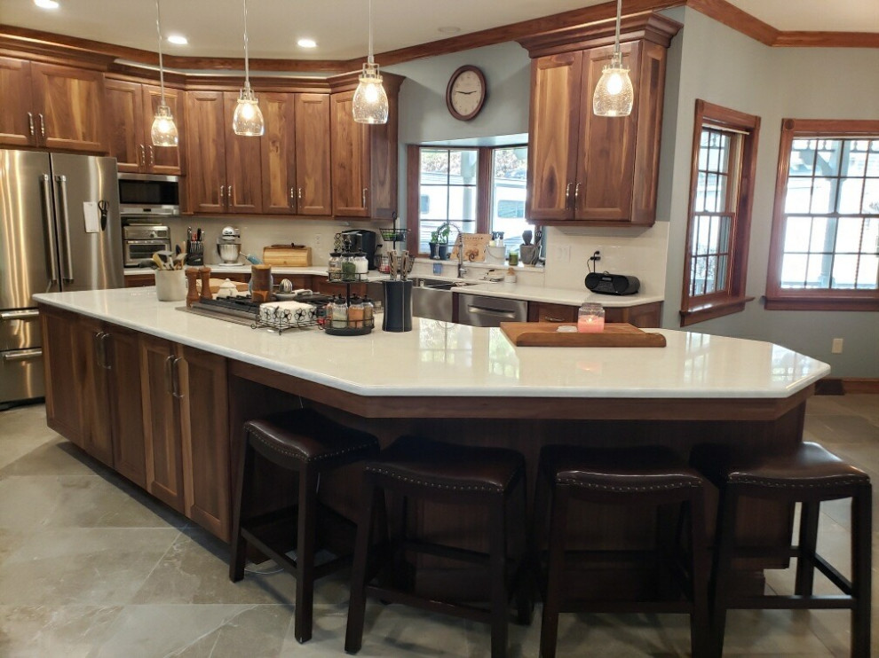 Klassisk inredning av ett vit vitt kök, med en rustik diskho, släta luckor, bruna skåp, bänkskiva i kvarts, vitt stänkskydd, stänkskydd i porslinskakel, rostfria vitvaror, klinkergolv i porslin, en köksö och beiget golv