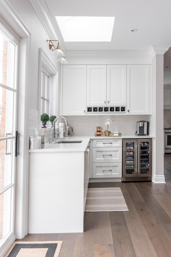 トロントにある広いトラディショナルスタイルのおしゃれなキッチン (ドロップインシンク、シェーカースタイル扉のキャビネット、白いキャビネット、クオーツストーンカウンター、白いキッチンパネル、セラミックタイルのキッチンパネル、シルバーの調理設備、濃色無垢フローリング、茶色い床、白いキッチンカウンター) の写真