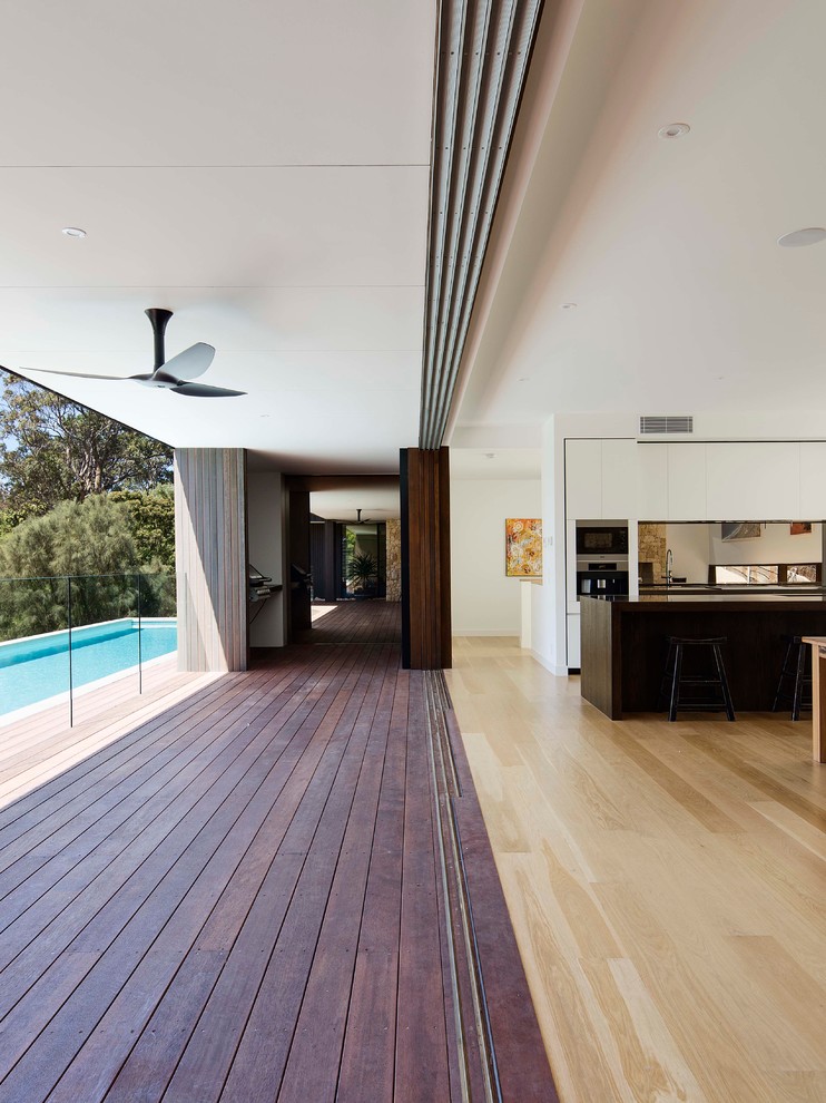 Photo of a large contemporary backyard deck in Melbourne with a vertical garden and a roof extension.