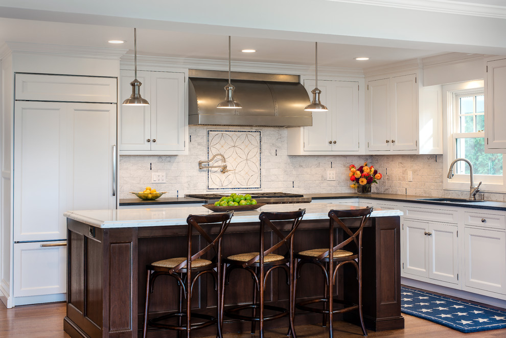 Mid-sized elegant l-shaped medium tone wood floor eat-in kitchen photo in Other with white cabinets, marble countertops, multicolored backsplash, paneled appliances, an island, an undermount sink and recessed-panel cabinets