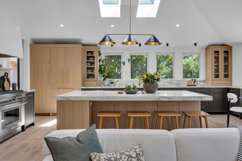 Open concept kitchen - mid-sized transitional l-shaped light wood floor, beige floor and vaulted ceiling open concept kitchen idea in San Francisco with flat-panel cabinets, light wood cabinets, white backsplash, paneled appliances, an island, white countertops, an undermount sink, quartz countertops and quartz backsplash