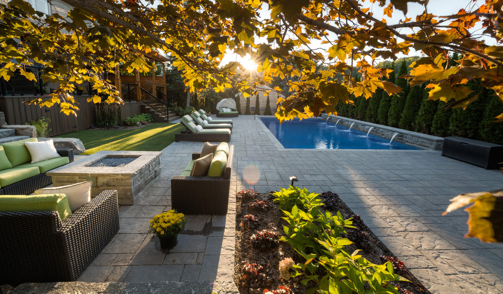 Inspiration for a large transitional backyard brick patio fountain remodel in Toronto with a pergola