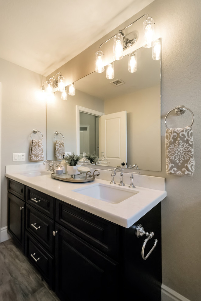 This is an example of a mid-sized traditional kids bathroom in Phoenix with raised-panel cabinets, black cabinets, an alcove tub, a shower/bathtub combo, a one-piece toilet, beige tile, subway tile, grey walls, porcelain floors, a drop-in sink, quartzite benchtops, grey floor and a shower curtain.