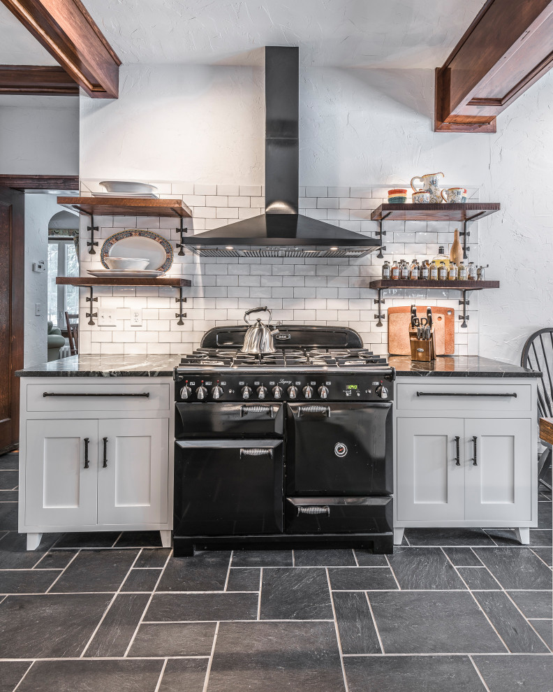 Design ideas for a large country u-shaped eat-in kitchen in Other with a farmhouse sink, recessed-panel cabinets, white cabinets, quartz benchtops, white splashback, ceramic splashback, black appliances, slate floors, with island, black floor and black benchtop.