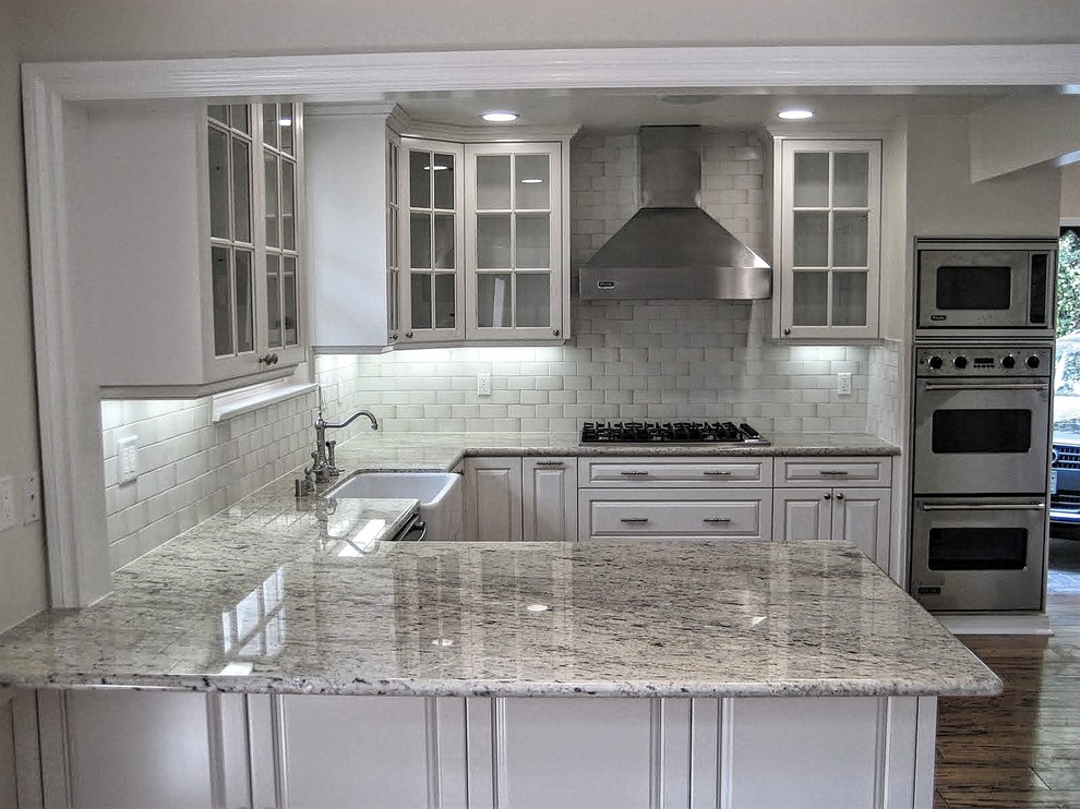 Photo of a mid-sized u-shaped kitchen in Los Angeles with a farmhouse sink and stainless steel appliances.