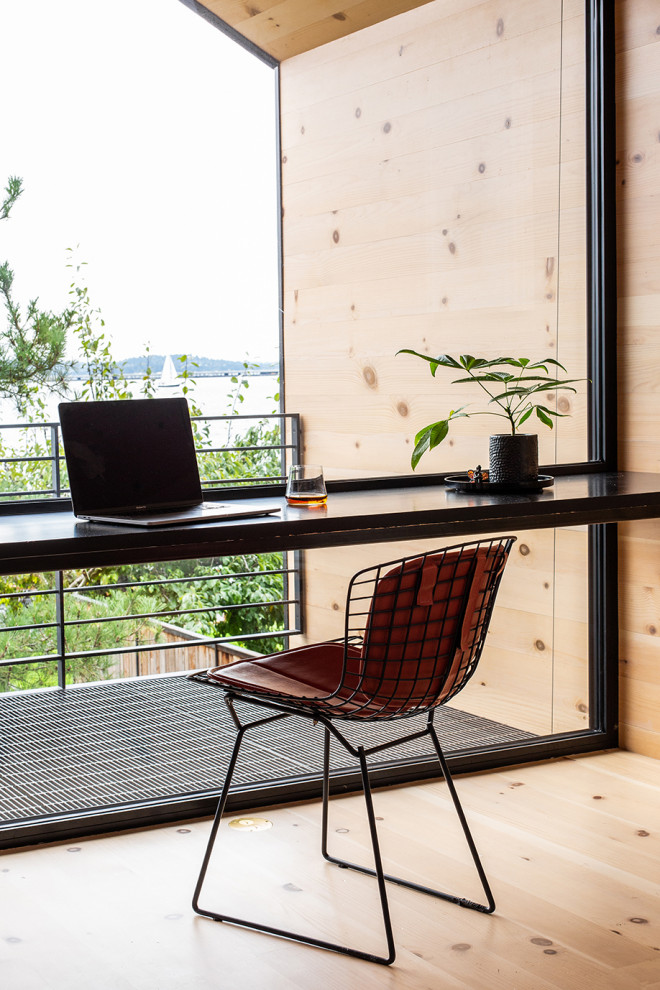 Diseño de estudio actual pequeño con suelo de madera clara, escritorio empotrado, madera y madera