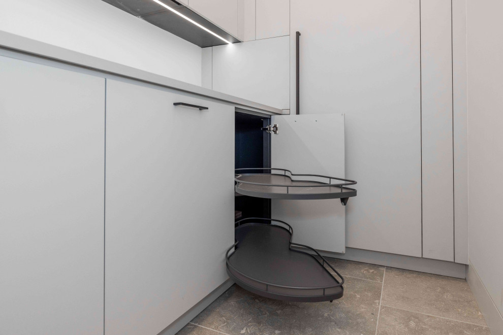 Inspiration for a small modern l-shaped kitchen pantry with an undermount sink, flat-panel cabinets, white cabinets, laminate benchtops, white splashback, black appliances, ceramic floors, no island, beige floor and white benchtop.