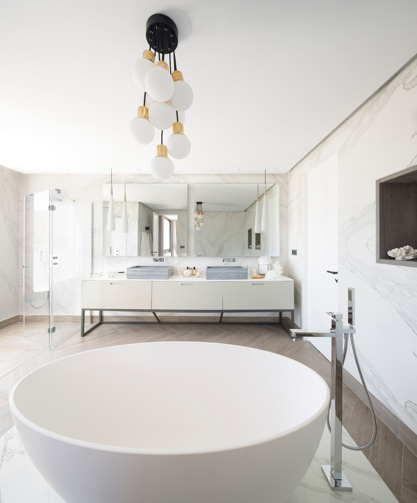 Contemporary master bathroom in Bilbao with flat-panel cabinets, white cabinets, a freestanding tub, a curbless shower, a vessel sink and a hinged shower door.