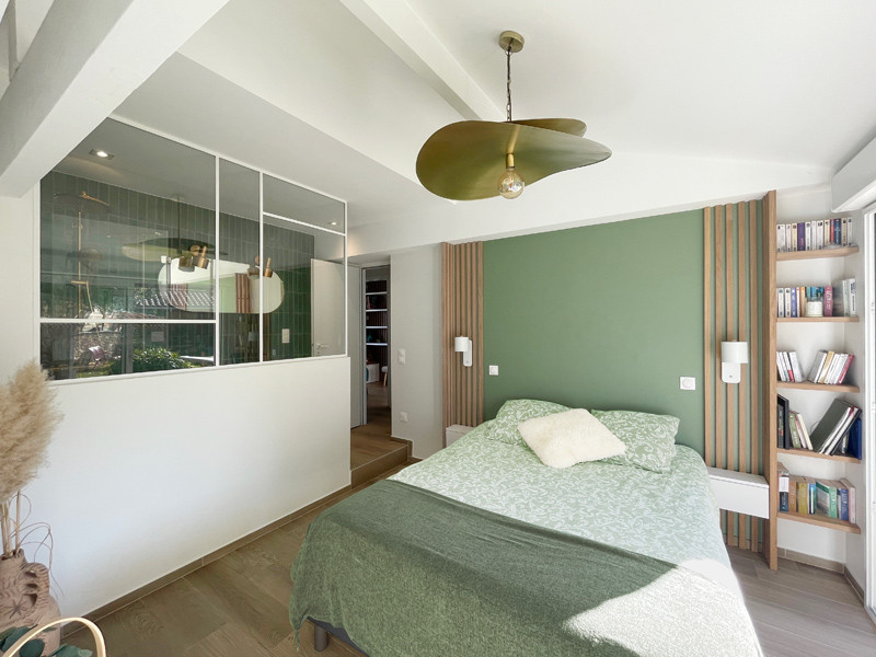 На фото: большая хозяйская спальня в белых тонах с отделкой деревом в скандинавском стиле с зелеными стенами, светлым паркетным полом и балками на потолке с