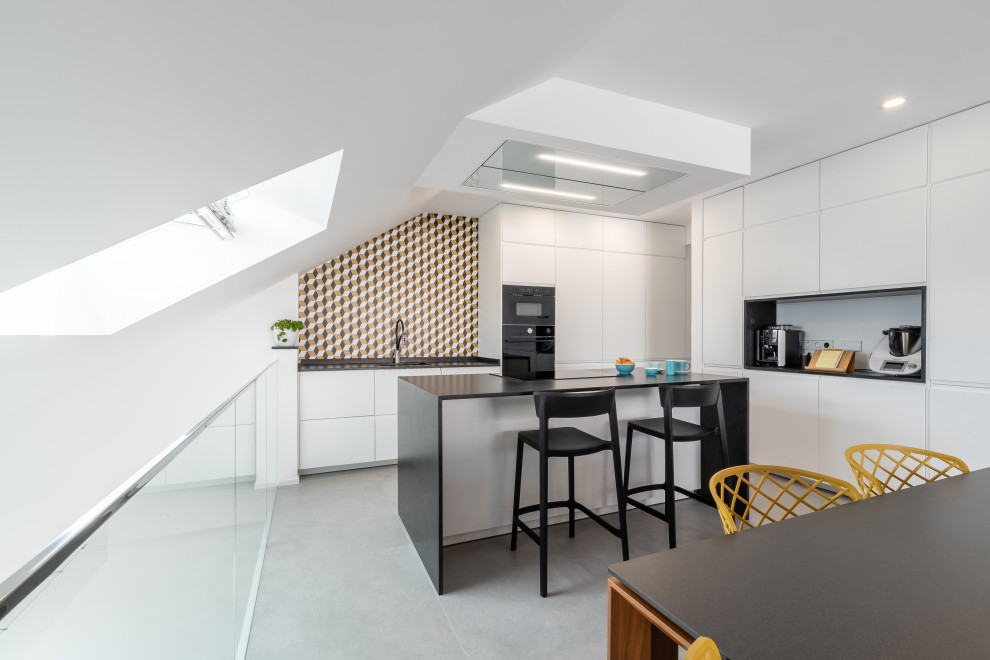 Inspiration for a large contemporary l-shaped eat-in kitchen in Other with an undermount sink, flat-panel cabinets, white cabinets, quartz benchtops, porcelain floors, with island, black benchtop, multi-coloured splashback, black appliances and grey floor.