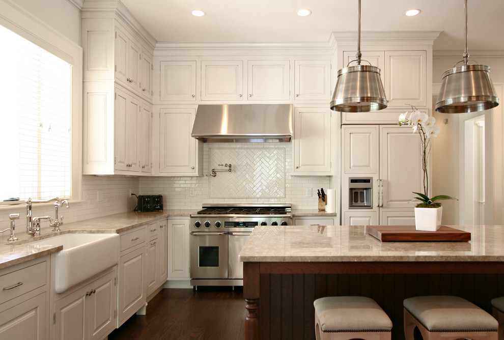 Photo of a traditional l-shaped kitchen in Atlanta with a farmhouse sink, panelled appliances, raised-panel cabinets, white cabinets, marble benchtops, white splashback and subway tile splashback.