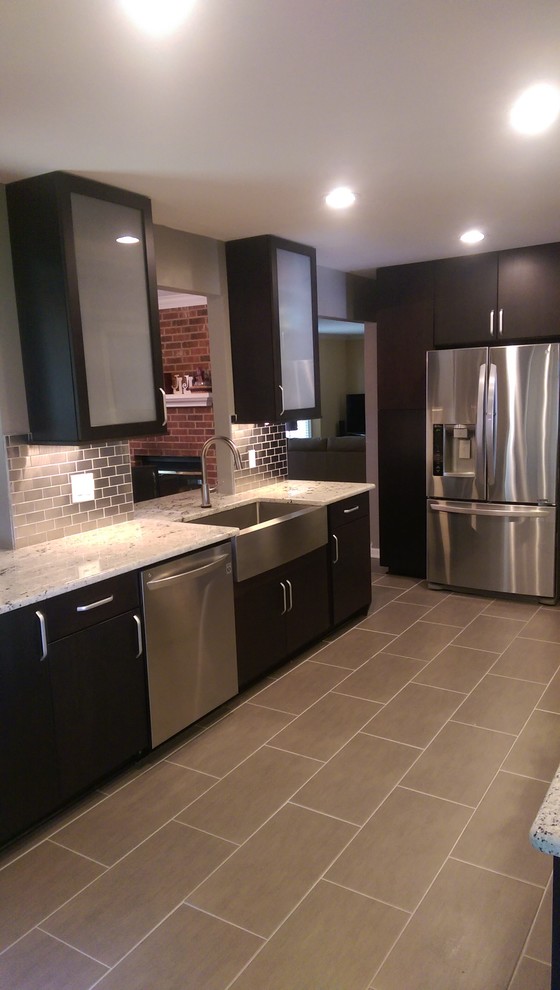 Photo of a small modern galley kitchen in Raleigh with a farmhouse sink, flat-panel cabinets, dark wood cabinets, granite benchtops, metallic splashback, subway tile splashback, stainless steel appliances and porcelain floors.
