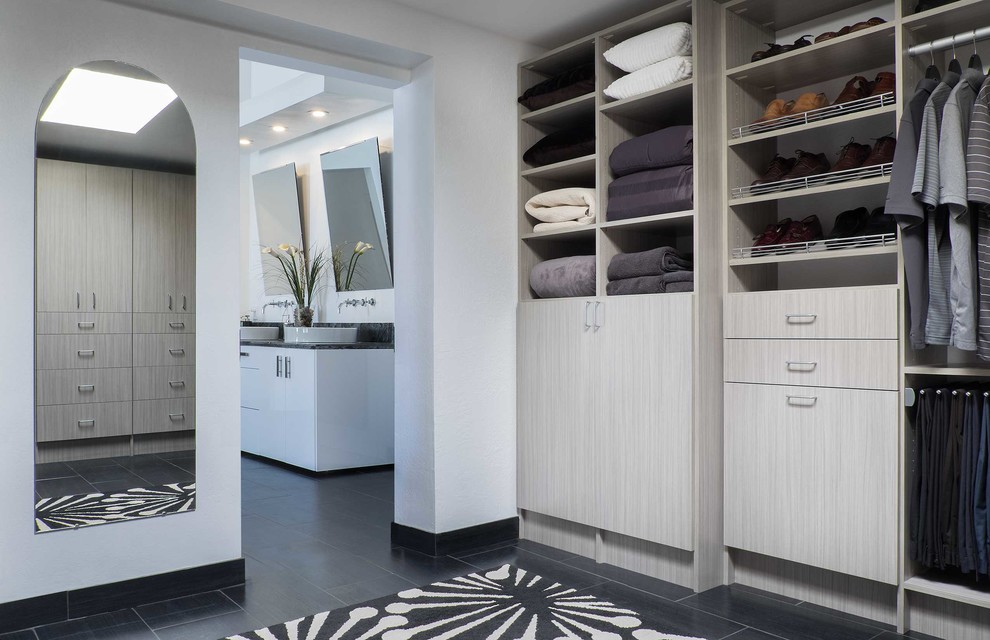 This is an example of a mid-sized transitional men's walk-in wardrobe in Phoenix with flat-panel cabinets, grey cabinets and slate floors.