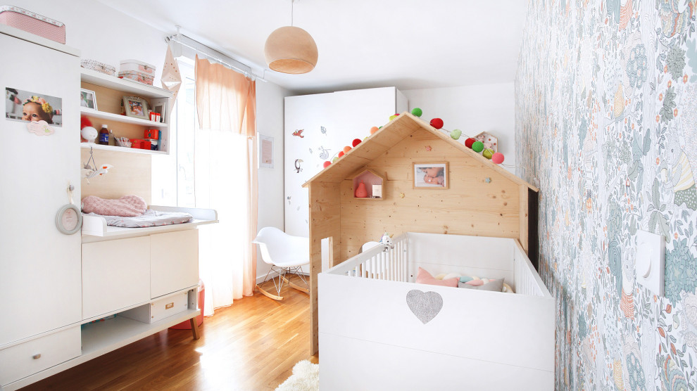 This is an example of a large contemporary nursery for girls in Paris with multi-coloured walls, laminate floors, wallpaper, brown floor and wallpaper.