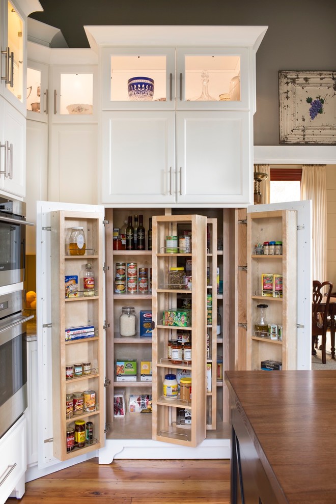 Photo of a large country kitchen pantry in Atlanta with recessed-panel cabinets, white cabinets, stainless steel appliances, medium hardwood floors and with island.