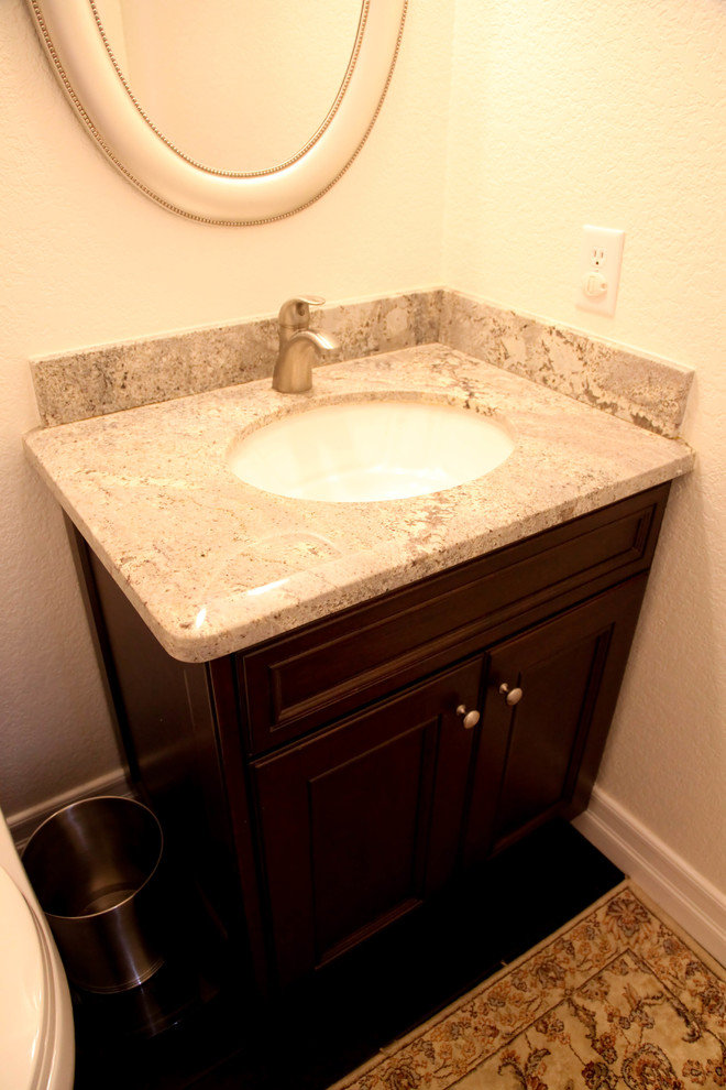 Powder room - small transitional dark wood floor powder room idea in Orange County with an undermount sink, recessed-panel cabinets, dark wood cabinets, granite countertops, a two-piece toilet and beige walls