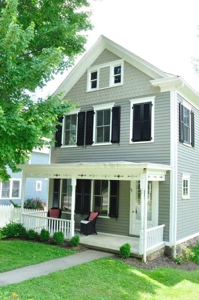 This is an example of a small traditional two-storey grey exterior in New York with wood siding and a gable roof.