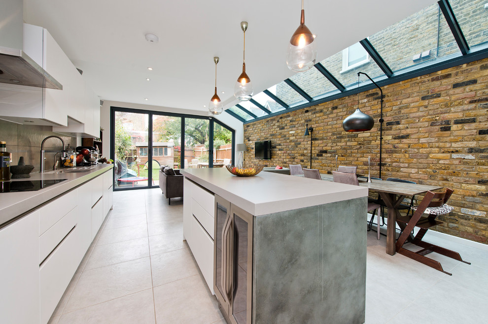 Photo of a mid-sized contemporary open plan kitchen in London with an integrated sink, flat-panel cabinets, white cabinets, solid surface benchtops, metallic splashback, with island, metal splashback and beige floor.