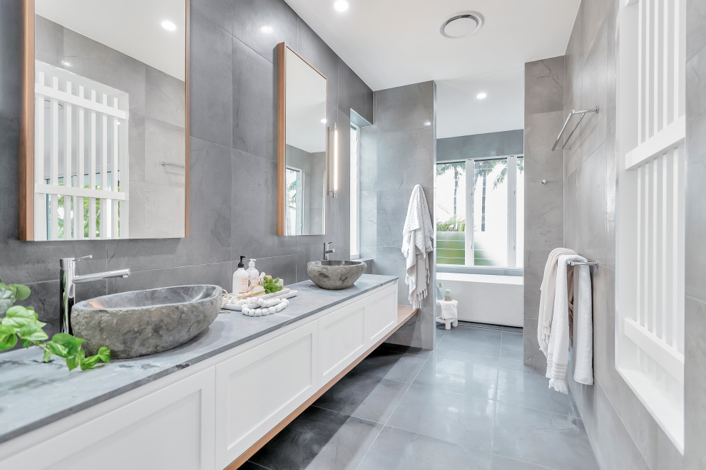 This is an example of a transitional master wet room bathroom in Other with shaker cabinets, white cabinets, a freestanding tub, grey walls, a vessel sink, grey floor, an open shower, grey benchtops, a double vanity and a floating vanity.