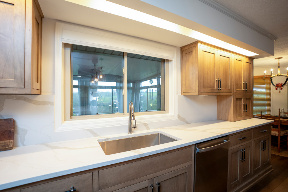 Large transitional l-shaped medium tone wood floor and brown floor eat-in kitchen photo with a single-bowl sink, shaker cabinets, medium tone wood cabinets, quartz countertops, white backsplash, quartz backsplash, stainless steel appliances, an island and white countertops