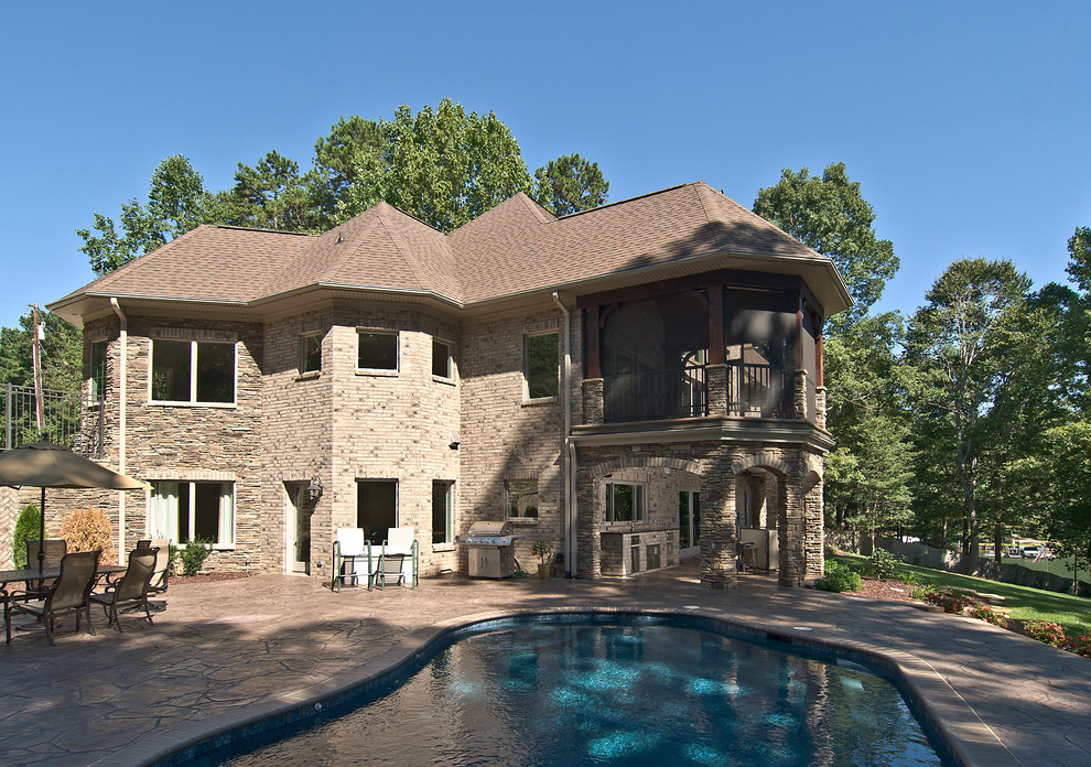 Large traditional side yard custom-shaped natural pool in Charlotte with stamped concrete.