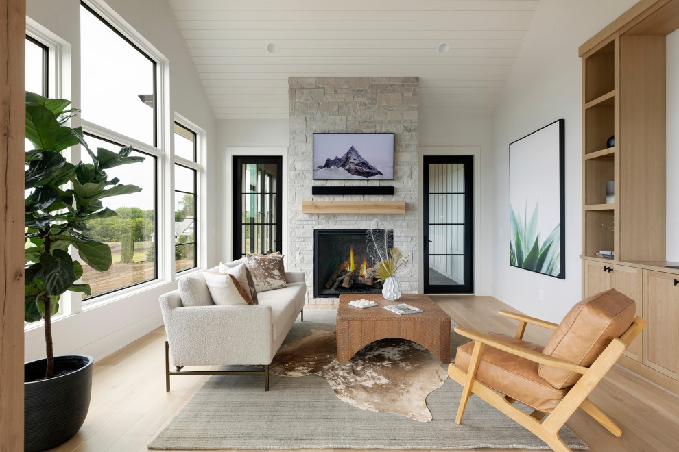 Inspiration for a transitional light wood floor sunroom remodel in Minneapolis with a two-sided fireplace and a stone fireplace