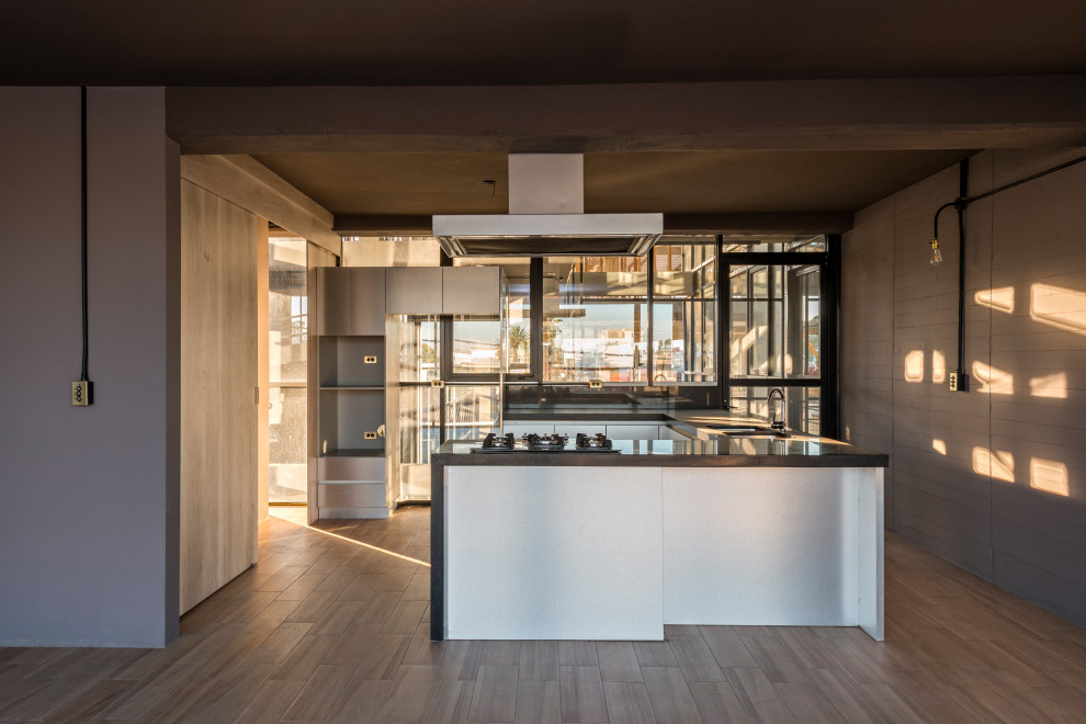 Medium sized modern u-shaped kitchen/diner in Other with flat-panel cabinets, light wood cabinets, a breakfast bar, a submerged sink, soapstone worktops, brown splashback, mirror splashback, black appliances, ceramic flooring, brown floors, brown worktops and exposed beams.