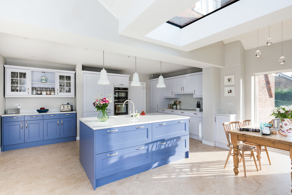 Large transitional single-wall open plan kitchen in Buckinghamshire with a double-bowl sink, shaker cabinets, blue cabinets, quartzite benchtops, white splashback, subway tile splashback, black appliances, porcelain floors, with island, beige floor and yellow benchtop.