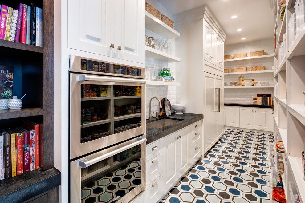 Design ideas for an expansive transitional l-shaped kitchen in Salt Lake City with white cabinets, an undermount sink, raised-panel cabinets, white splashback, subway tile splashback, panelled appliances, multi-coloured floor and black benchtop.
