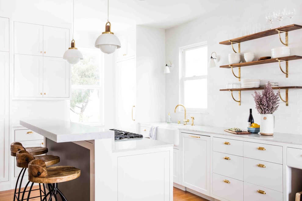 Inspiration for a transitional kitchen in San Francisco with a farmhouse sink, marble benchtops, white splashback, with island, open cabinets and medium hardwood floors.