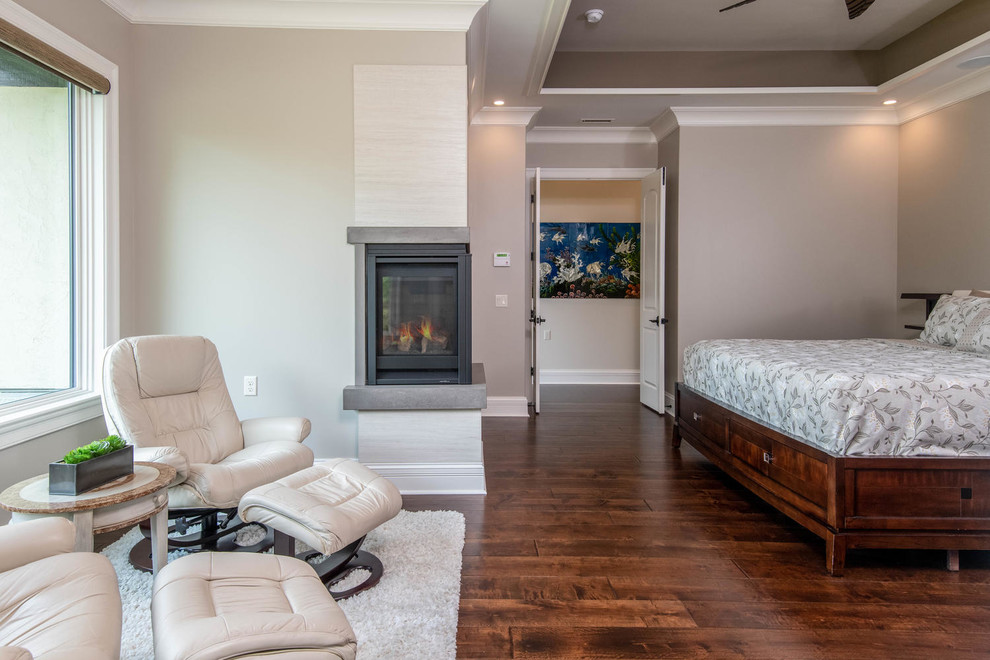 Large transitional master bedroom in Other with beige walls, dark hardwood floors, a corner fireplace, a concrete fireplace surround and brown floor.