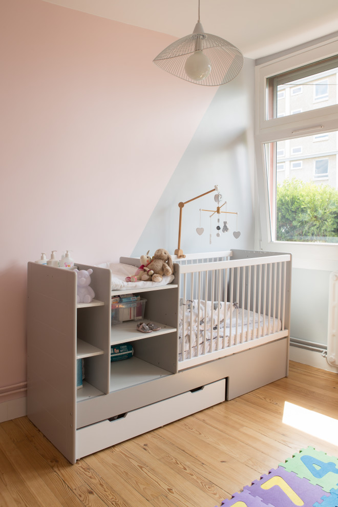 Inspiration for a mid-sized contemporary nursery for girls in Paris with pink walls and light hardwood floors.