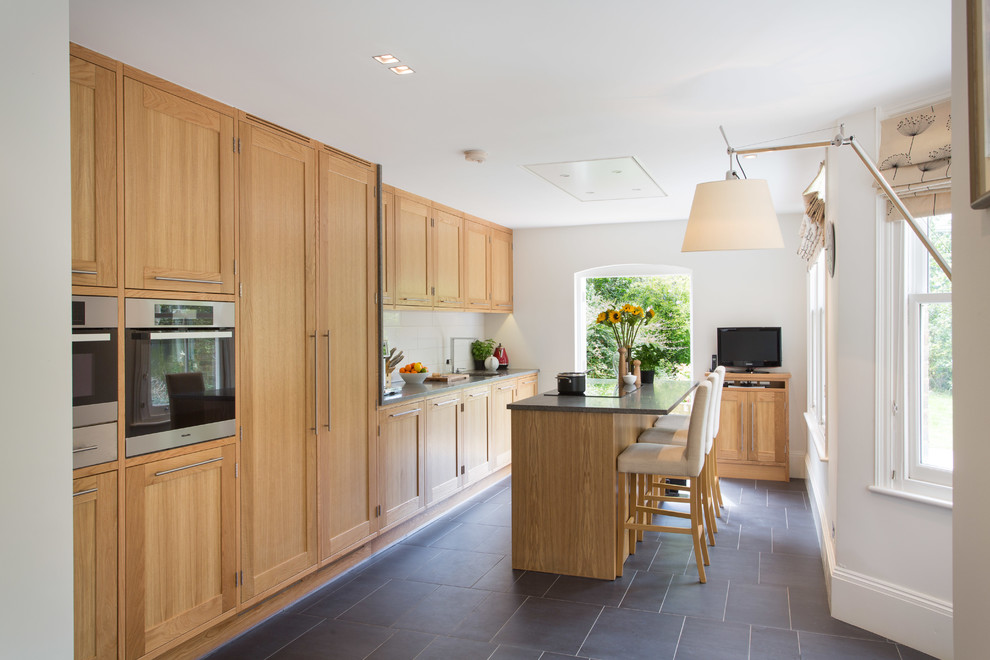 Inspiration for a transitional galley separate kitchen in Other with an undermount sink, medium wood cabinets, granite benchtops, white splashback, ceramic splashback, stainless steel appliances, shaker cabinets, slate floors and with island.