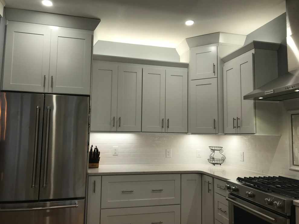 Inspiration for a mid-sized transitional u-shaped medium tone wood floor kitchen remodel in Charlotte with an undermount sink, shaker cabinets, white cabinets, quartz countertops, white backsplash, subway tile backsplash, stainless steel appliances and a peninsula