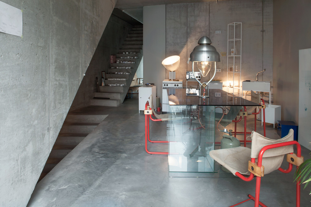 This is an example of a mid-sized industrial dining room in Berlin with grey walls and concrete floors.