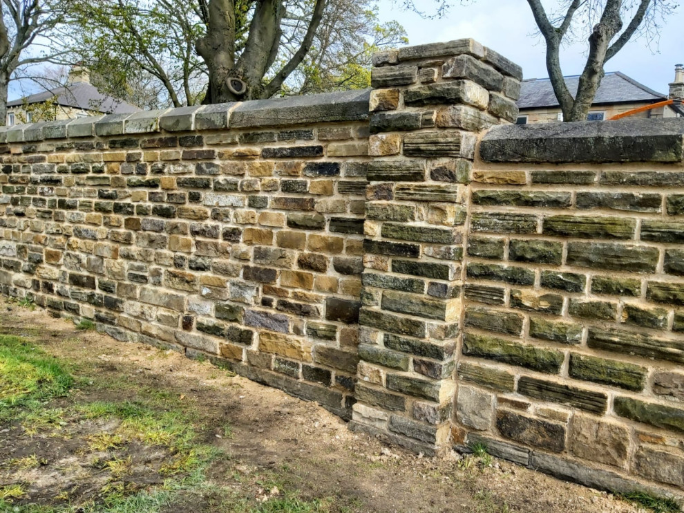This is an example of a mid-sized traditional front yard driveway in Other with a stone fence.