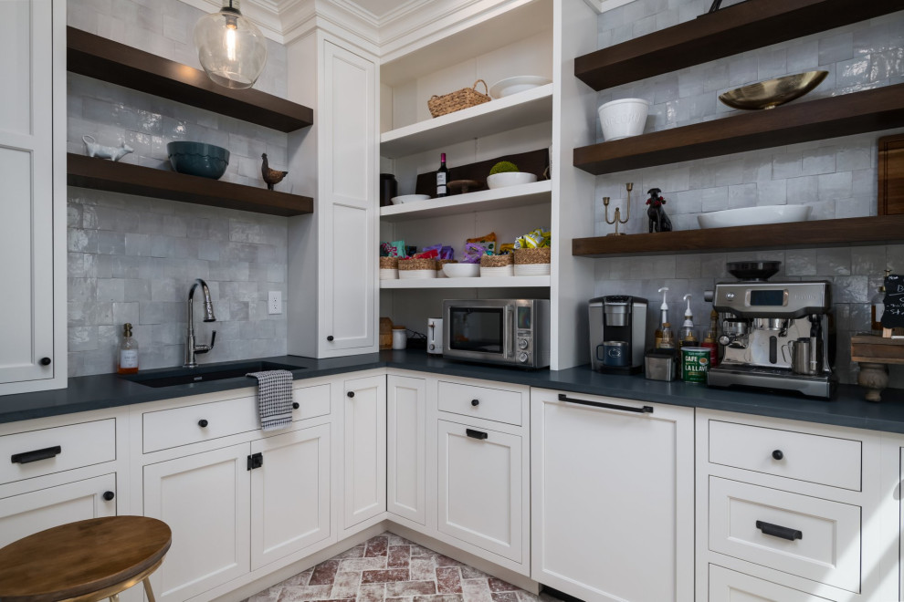 Medium sized traditional u-shaped kitchen pantry in Other with a submerged sink, flat-panel cabinets, white cabinets, engineered stone countertops, white splashback, porcelain splashback, integrated appliances, brick flooring, red floors and black worktops.