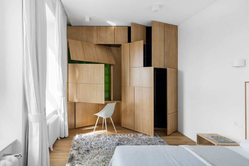 This is an example of a contemporary master bedroom in Moscow with white walls, medium hardwood floors and brown floor.