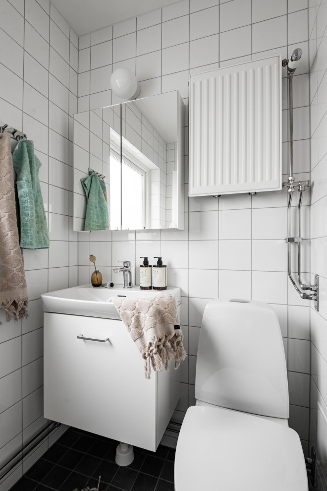 Inspiration för minimalistiska badrum, med släta luckor, vita skåp, en toalettstol med separat cisternkåpa, vit kakel, ett konsol handfat och svart golv