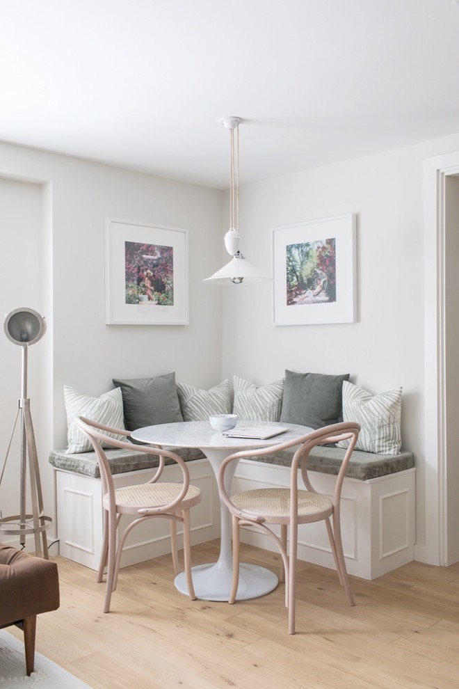 This is an example of a scandinavian dining room in London with white walls, light hardwood floors and beige floor.