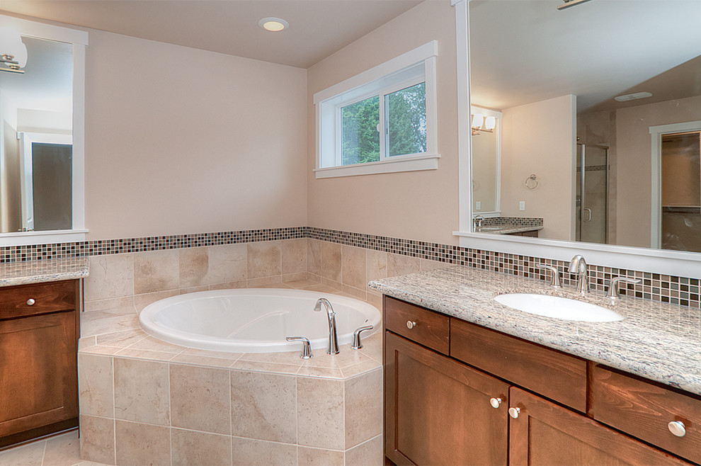 Inspiration for a traditional master bathroom in Seattle with shaker cabinets, brown cabinets, a drop-in tub, an alcove shower, brown tile, glass tile, ceramic floors, an undermount sink, granite benchtops, beige floor and a hinged shower door.