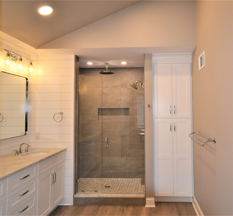 Inspiration for a large transitional master beige tile and ceramic tile vinyl floor, brown floor, double-sink and shiplap wall bathroom remodel in Philadelphia with shaker cabinets, white cabinets, a one-piece toilet, beige walls, an undermount sink, quartz countertops, a hinged shower door, beige countertops and a built-in vanity