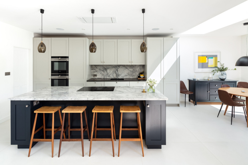 Design ideas for a mid-sized transitional galley open plan kitchen in London with an integrated sink, shaker cabinets, grey cabinets, grey splashback, panelled appliances, porcelain floors, with island, grey floor and black benchtop.