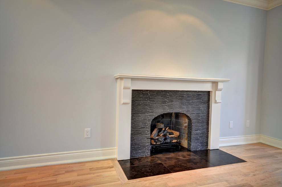 This is an example of a mid-sized traditional enclosed family room in Toronto with light hardwood floors, a standard fireplace, a stone fireplace surround and blue walls.