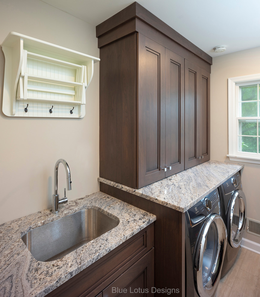 This is an example of a small transitional galley utility room in Philadelphia with an undermount sink, recessed-panel cabinets, medium wood cabinets, granite benchtops, beige walls, porcelain floors, a side-by-side washer and dryer, multi-coloured floor and multi-coloured benchtop.