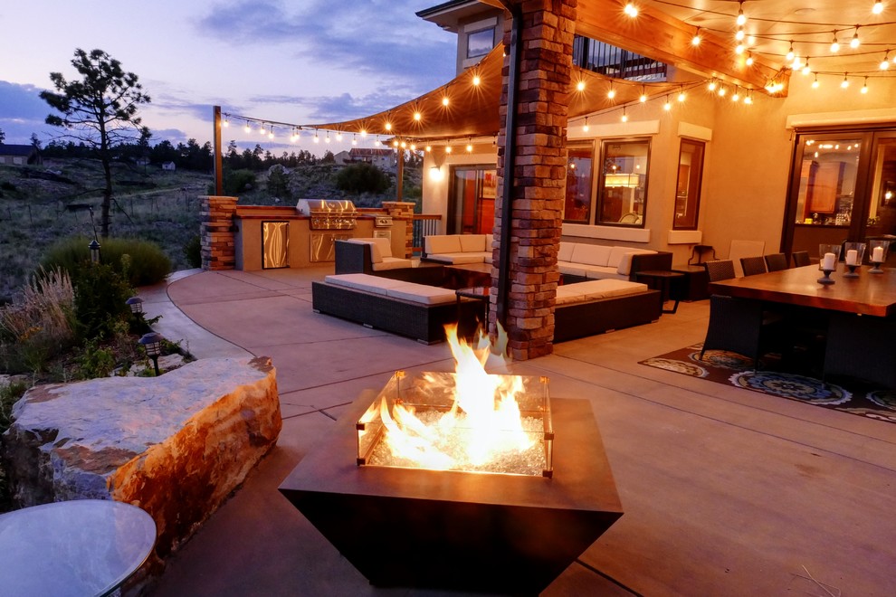 Photo of a large backyard patio in Denver with an outdoor kitchen, concrete slab and an awning.