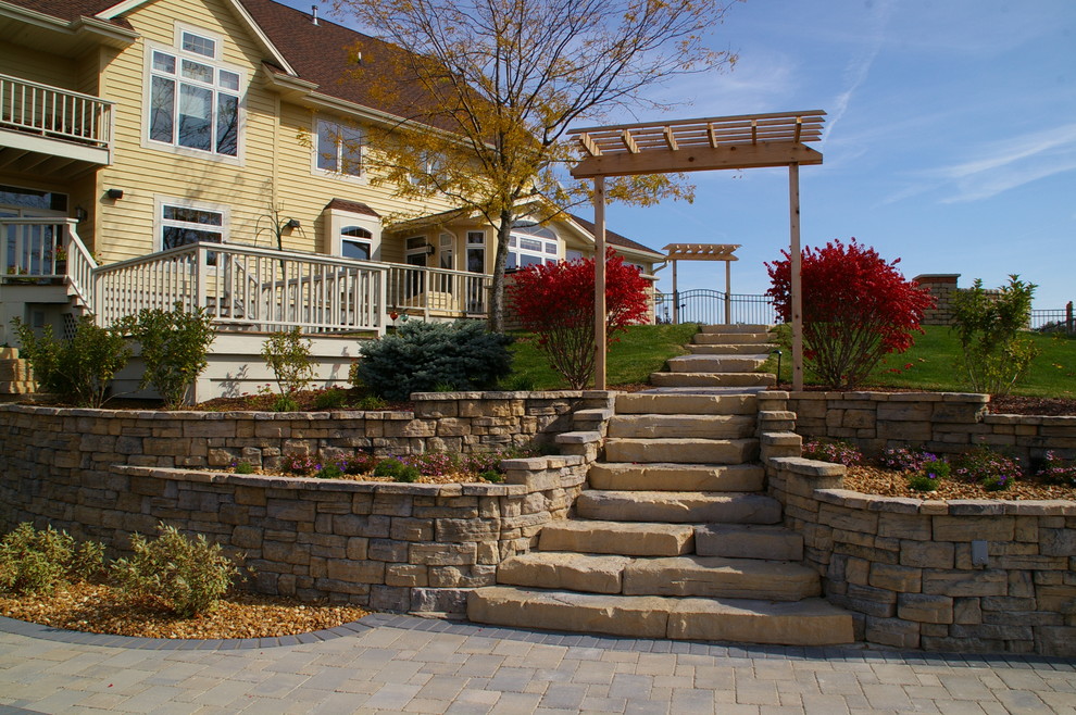 Inspiration for a traditional backyard garden in Milwaukee with a retaining wall and brick pavers.